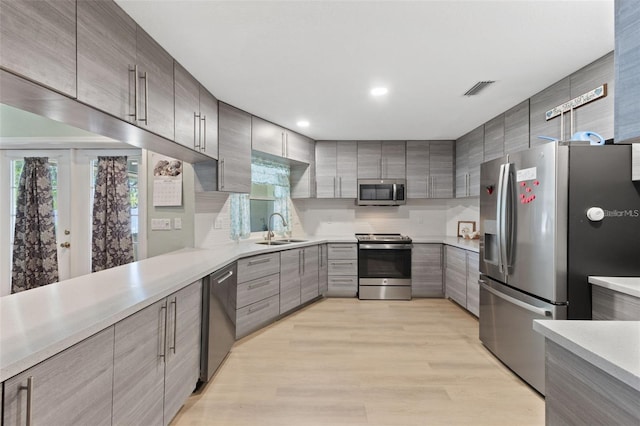 7222 Stanford Dr, Lakeland, FL 33809 - kitchen with stainless steel appliances, a sink, light countertops, decorative backsplash, and light wood-style flooring