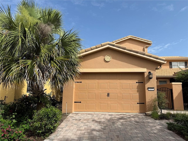 2495 Palm Tree Dr, Kissimmee, FL 34759 - view of front of house with stucco siding, driveway, an attached garage, a tile roof, and a gate