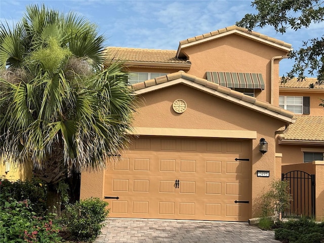 2495 Palm Tree Dr, Kissimmee, FL 34759 - view of front of house with decorative driveway, a tile roof, a garage, stucco siding, and a gate
