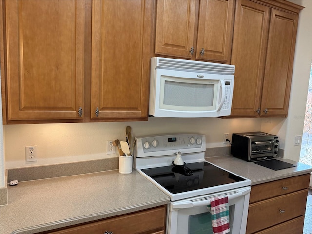 2495 Palm Tree Dr, Kissimmee, FL 34759 - kitchen featuring white appliances, light countertops, and brown cabinetry