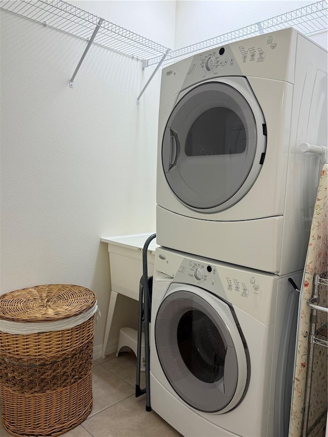 2495 Palm Tree Dr, Kissimmee, FL 34759 - laundry room featuring estacked washer and dryer, light tile patterned flooring, and baseboards