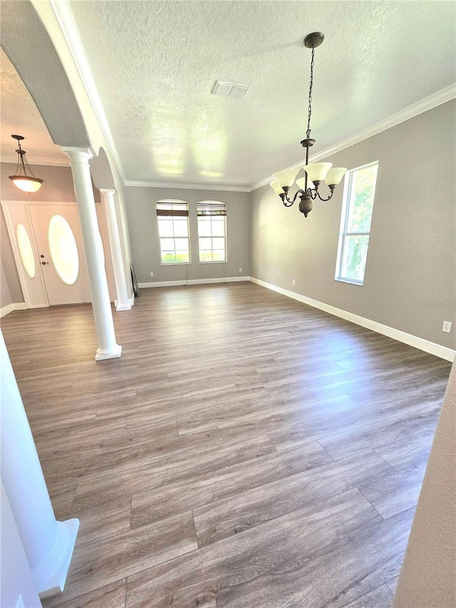 5704 Ansley Way, Mount Dora, FL 32757 - unfurnished living room with a chandelier, crown molding, decorative columns, a textured ceiling, and baseboards