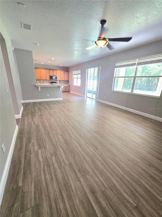 5704 Ansley Way, Mount Dora, FL 32757 - unfurnished living room with dark wood-style floors, baseboards, healthy amount of natural light, and a textured ceiling