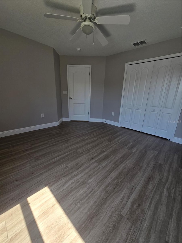 5704 Ansley Way, Mount Dora, FL 32757 - unfurnished bedroom featuring dark wood-style floors, baseboards, a closet, a textured ceiling, and ceiling fan