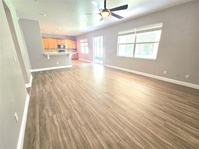 5704 Ansley Way, Mount Dora, FL 32757 - unfurnished living room with baseboards, light wood-style floors, and a ceiling fan