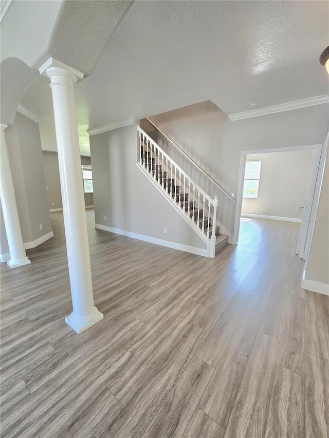 5704 Ansley Way, Mount Dora, FL 32757 - unfurnished living room with ornate columns, crown molding, a textured ceiling, stairs, and baseboards