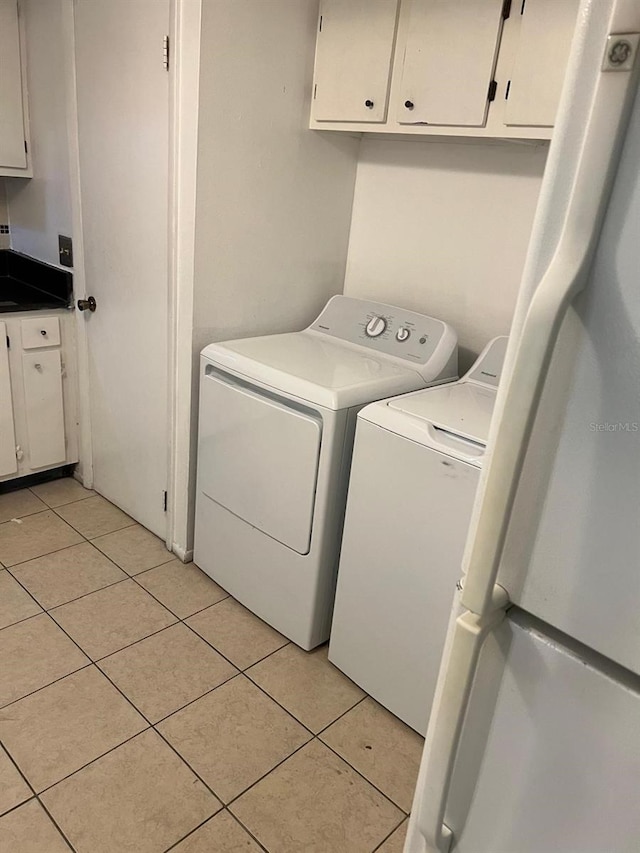 washroom with independent washer and dryer, cabinet space, and light tile patterned floors
