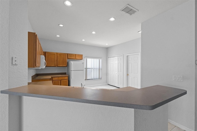 16614 Lazy Breeze Loop, Clermont, FL 34714 - kitchen featuring white appliances, brown cabinetry, recessed lighting, a peninsula, and a sink