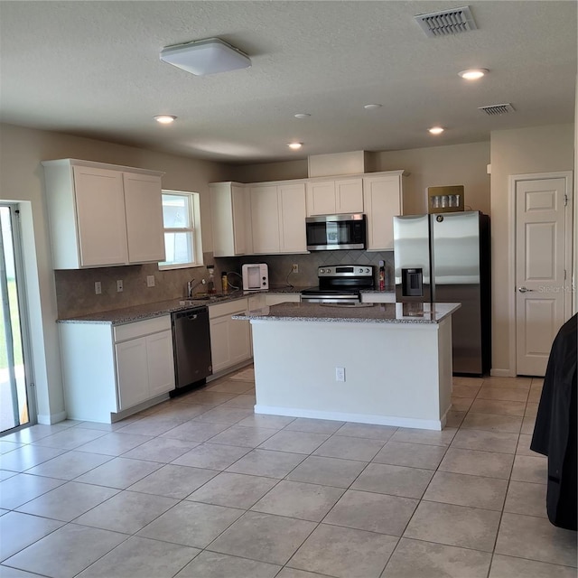 1556 Aspen Ave, Davenport, FL 33837 - kitchen with appliances with stainless steel finishes, backsplash, white cabinets, dark stone countertops, and recessed lighting