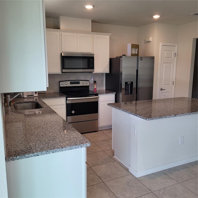 1556 Aspen Ave, Davenport, FL 33837 - kitchen featuring appliances with stainless steel finishes, a sink, white cabinets, dark stone counters, and backsplash