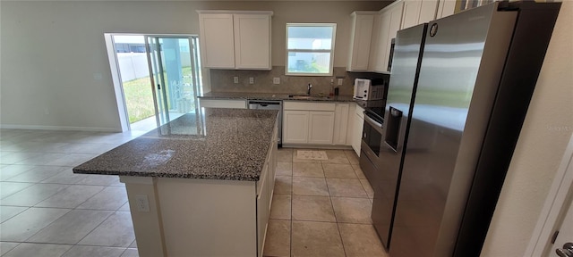1556 Aspen Ave, Davenport, FL 33837 - kitchen featuring stainless steel appliances, a sink, a kitchen island, dark stone counters, and backsplash