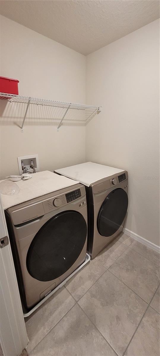 1556 Aspen Ave, Davenport, FL 33837 - washroom featuring separate washer and dryer, tile patterned floors, baseboards, and a textured ceiling