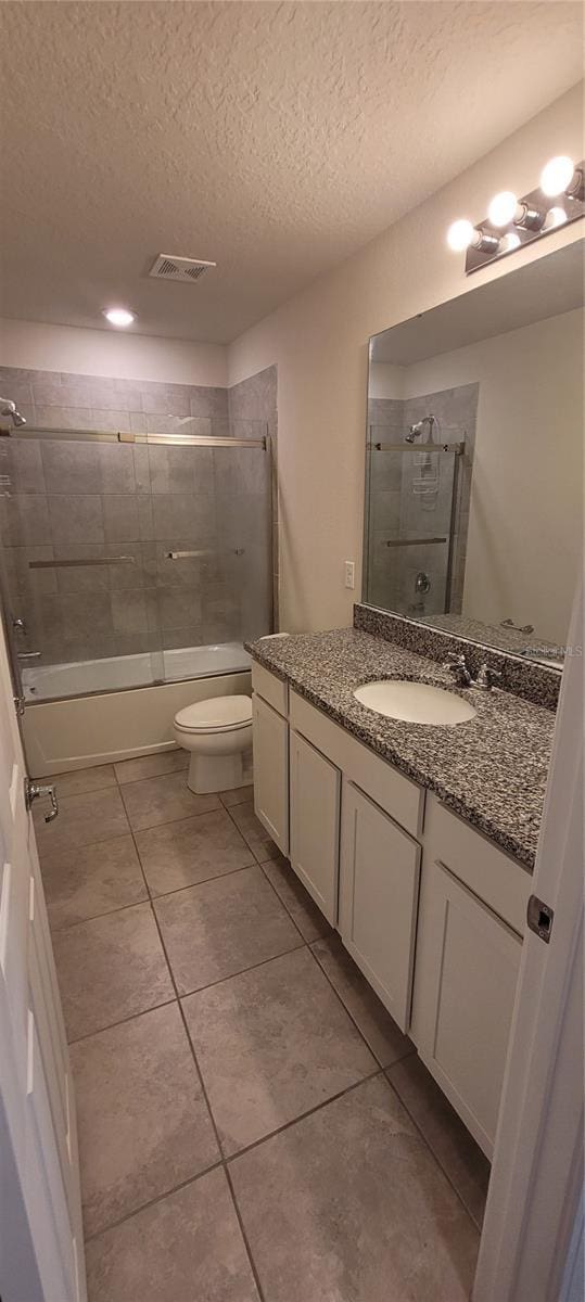 1556 Aspen Ave, Davenport, FL 33837 - bathroom with vanity, shower / bath combination, toilet, tile patterned flooring, and a textured ceiling