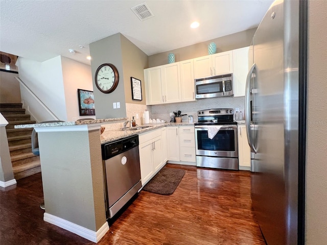 5356 Diplomat Ct Unit 108, Kissimmee, FL 34746 - kitchen with stainless steel appliances, a peninsula, light stone counters, white cabinets, and recessed lighting