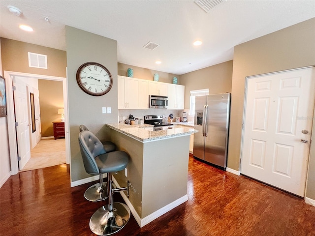 5356 Diplomat Ct Unit 108, Kissimmee, FL 34746 - kitchen featuring appliances with stainless steel finishes, white cabinets, dark wood-style floors, a peninsula, and recessed lighting