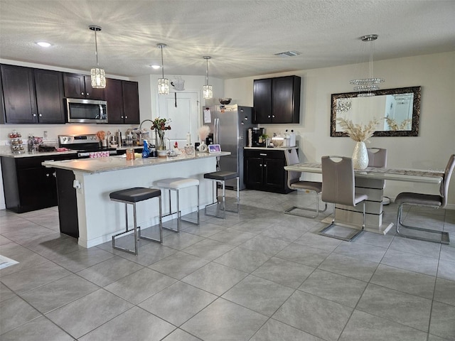 6315 Hillview Rd, Spring Hill, FL 34606 - kitchen with stainless steel appliances, a breakfast bar, light countertops, light tile patterned flooring, and decorative light fixtures
