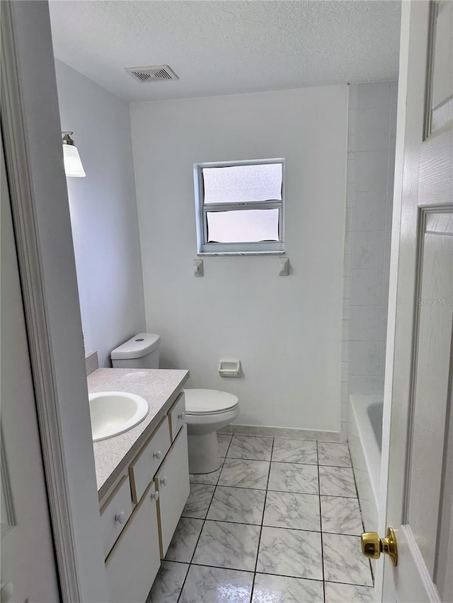 19 Rainbow Ln, Palm Coast, FL 32164 - bathroom featuring marble look tile flooring, vanity, toilet, a textured ceiling, and baseboards
