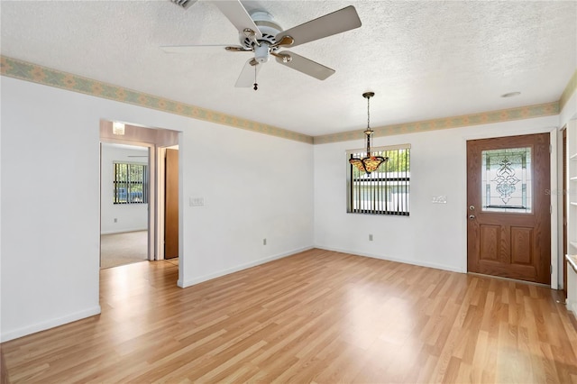 2740 Barker Rd, Saint Cloud, FL 34771 - unfurnished living room featuring plenty of natural light, light wood-type flooring, a textured ceiling, a chandelier, and ceiling fan