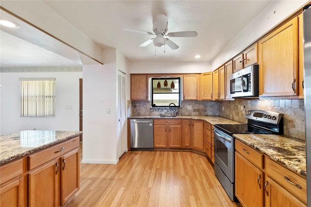 2740 Barker Rd, Saint Cloud, FL 34771 - kitchen with appliances with stainless steel finishes, light wood-style floors, a ceiling fan, backsplash, and light stone counters