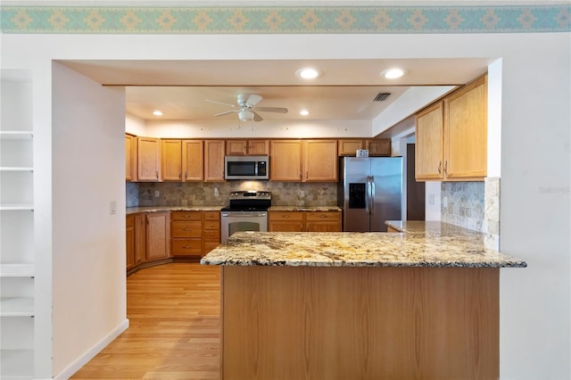2740 Barker Rd, Saint Cloud, FL 34771 - kitchen with stainless steel appliances, a peninsula, light wood-type flooring, ceiling fan, and light stone counters