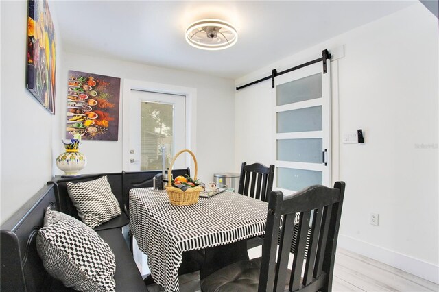 416 E Seminole Ave, Lake Wales, FL 33853 - dining space with a barn door, light wood-type flooring, and baseboards