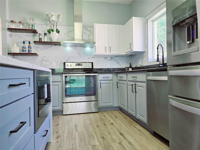 2312 Twickingham Ct, Clermont, FL 34711 - kitchen with stainless steel appliances, wall chimney exhaust hood, backsplash, and light wood-type flooring