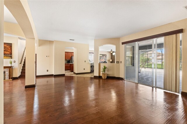 3759 Eagle Isle Cir, Kissimmee, FL 34746 - unfurnished living room with arched walkways, wood finished floors, stairway, and baseboards