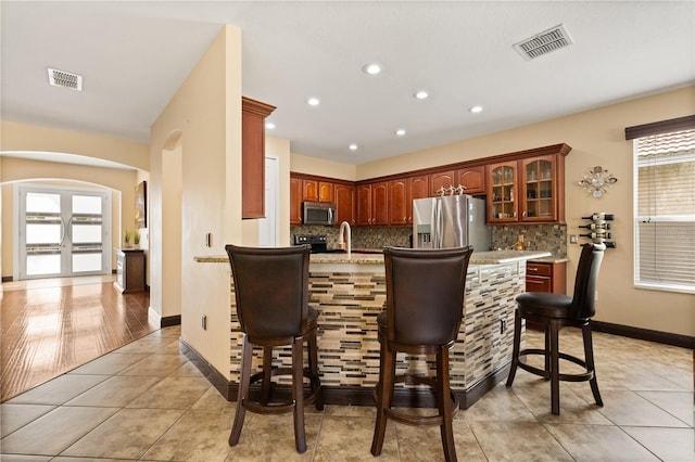 3759 Eagle Isle Cir, Kissimmee, FL 34746 - kitchen featuring appliances with stainless steel finishes, arched walkways, backsplash, a breakfast bar area, and light tile patterned floors
