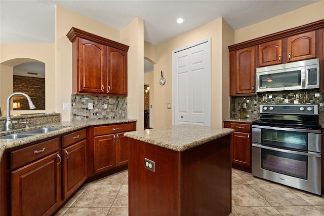 3759 Eagle Isle Cir, Kissimmee, FL 34746 - kitchen with appliances with stainless steel finishes, a sink, arched walkways, and backsplash