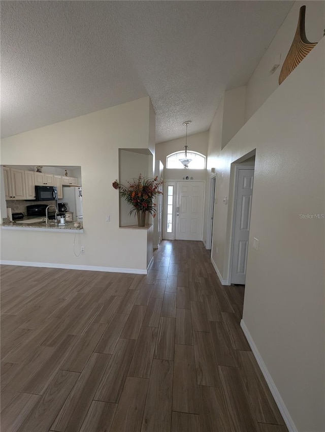 5921 Lake Champlain Dr, Orlando, FL 32829 - foyer entrance with lofted ceiling, dark wood finished floors, a textured ceiling, and baseboards