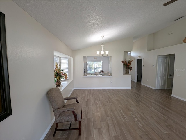 5921 Lake Champlain Dr, Orlando, FL 32829 - sitting room featuring lofted ceiling, a textured ceiling, a chandelier, wood finished floors, and baseboards