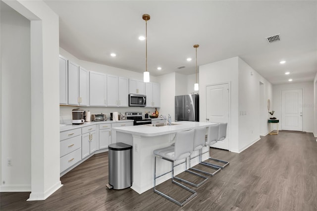 685 Overpool Ave, Davenport, FL 33896 - kitchen featuring appliances with stainless steel finishes, dark wood-style floors, an island with sink, light countertops, and recessed lighting