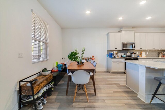 2224 Celebration Blvd, Celebration, FL 34747 - kitchen featuring appliances with stainless steel finishes, light wood finished floors, backsplash, recessed lighting, and white cabinetry