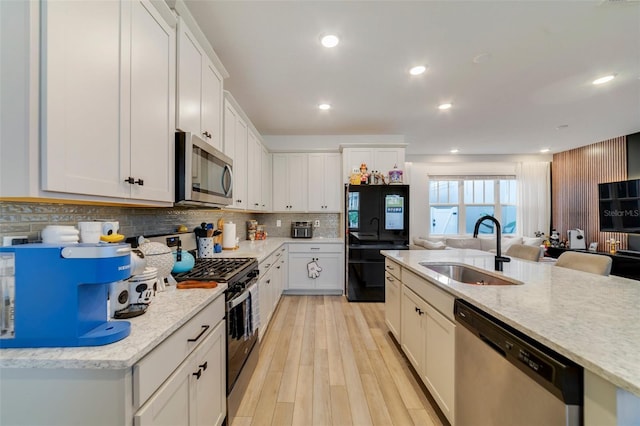 2224 Celebration Blvd, Celebration, FL 34747 - kitchen featuring appliances with stainless steel finishes, a sink, decorative backsplash, light wood-type flooring, and white cabinets