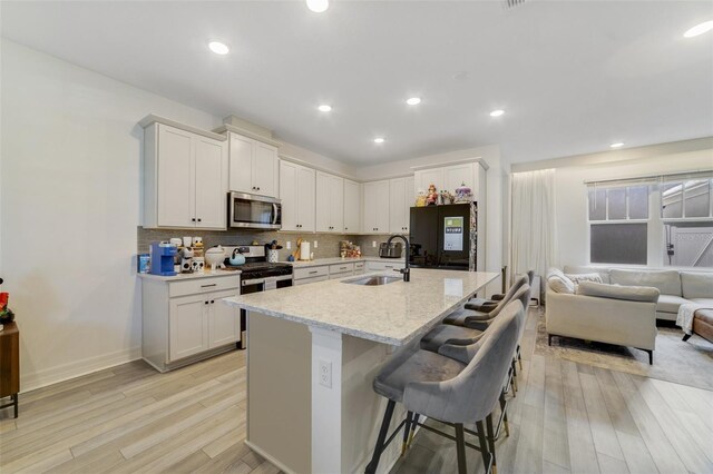 2224 Celebration Blvd, Celebration, FL 34747 - kitchen with stainless steel appliances, a sink, light wood-type flooring, a breakfast bar area, and backsplash