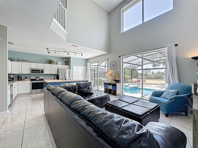 1426 Park Park, Haines City, FL 33844 - living room featuring healthy amount of natural light, light tile patterned flooring, a high ceiling, a textured ceiling, and rail lighting