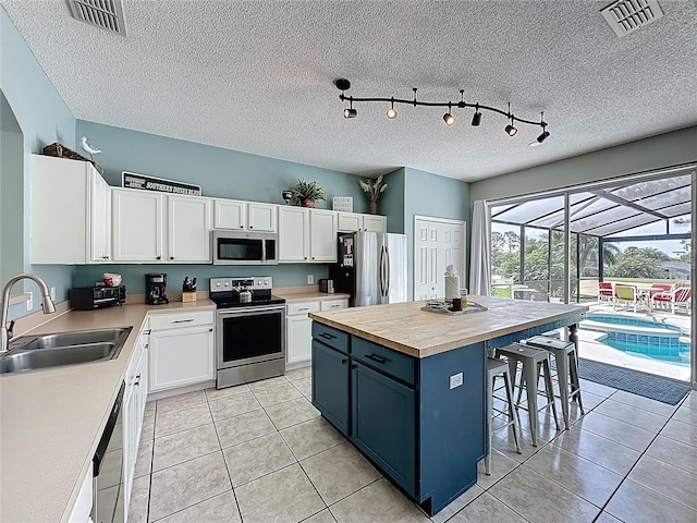 1426 Park Park, Haines City, FL 33844 - kitchen featuring stainless steel appliances, white cabinets, a textured ceiling, butcher block countertops, and a breakfast bar