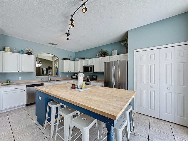 1426 Park Park, Haines City, FL 33844 - kitchen featuring appliances with stainless steel finishes, white cabinetry, a center island, light tile patterned floors, and a textured ceiling