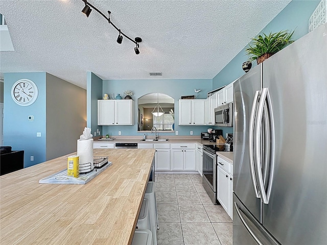 1426 Park Park, Haines City, FL 33844 - kitchen featuring appliances with stainless steel finishes, arched walkways, white cabinetry, a textured ceiling, and butcher block countertops