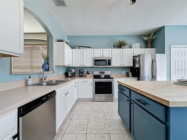 1426 Park Park, Haines City, FL 33844 - kitchen featuring appliances with stainless steel finishes, white cabinets, a textured ceiling, blue cabinetry, and arched walkways