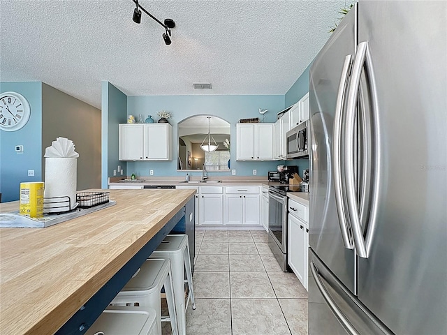1426 Park Park, Haines City, FL 33844 - kitchen with stainless steel appliances, white cabinets, a kitchen breakfast bar, arched walkways, and light tile patterned flooring