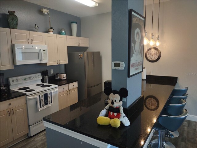8101 Coconut Palm Way Unit 303, Kissimmee, FL 34747 - kitchen with white appliances, dark wood-type flooring, dark countertops, a kitchen breakfast bar, and white cabinetry