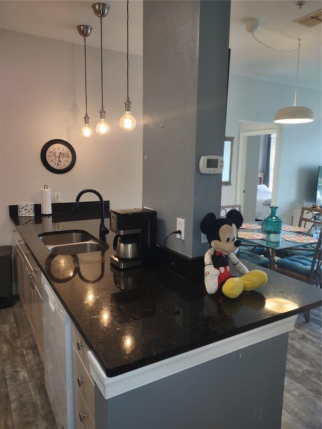 8101 Coconut Palm Way Unit 303, Kissimmee, FL 34747 - kitchen featuring a sink, dishwashing machine, dark wood-style flooring, pendant lighting, and a peninsula
