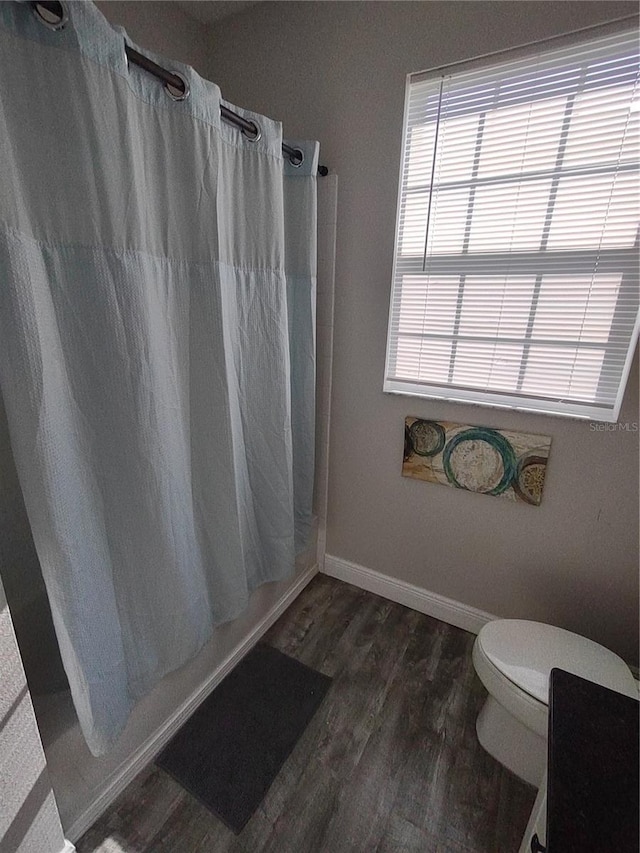 8101 Coconut Palm Way Unit 303, Kissimmee, FL 34747 - bathroom featuring wood finished floors, toilet, a shower with curtain, and baseboards