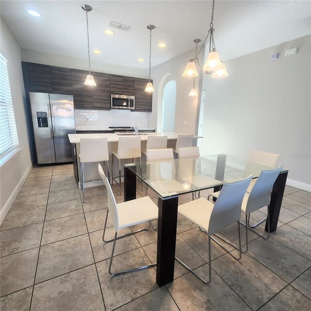 191 Aidans Lndg, Haines City, FL 33844 - dining room with baseboards, arched walkways, a textured ceiling, recessed lighting, and light tile patterned floors