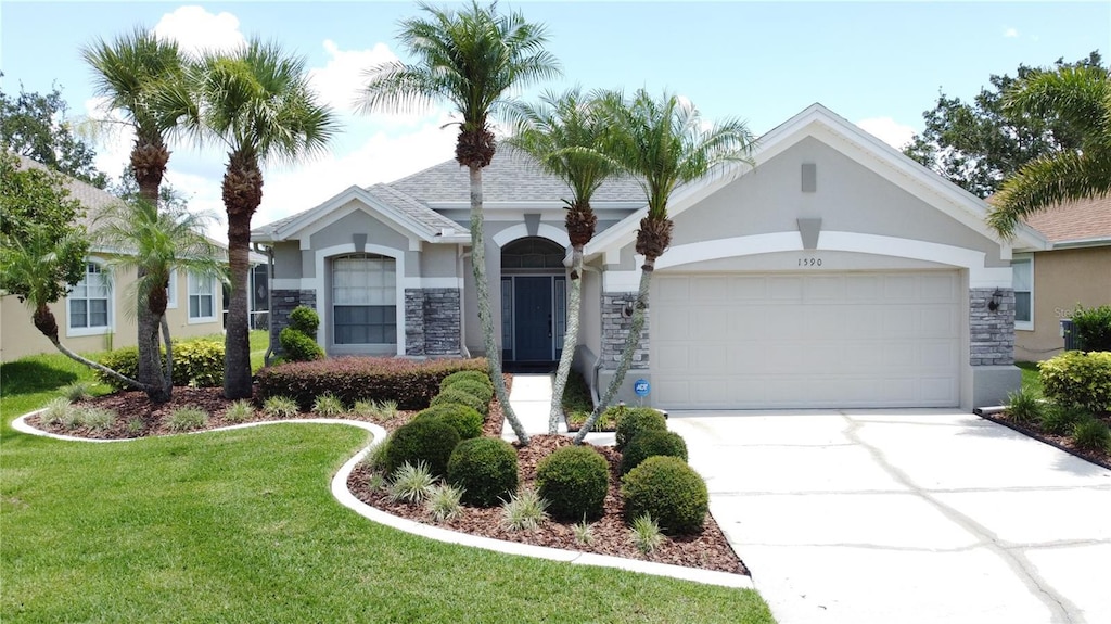 1590 The Oaks Blvd, Kissimmee, FL 34746 - ranch-style house featuring stucco siding, a front lawn, a garage, and concrete driveway