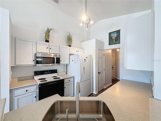 1428 Park Pl, Haines City, FL 33844 - kitchen featuring stainless steel microwave, range with electric stovetop, freestanding refrigerator, high vaulted ceiling, and white cabinets
