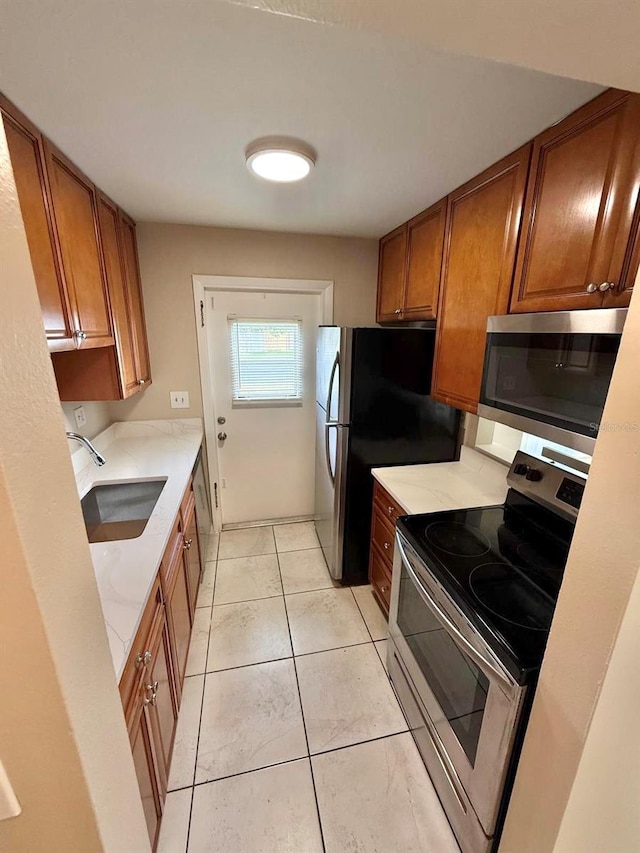 1001 Plantation Dr Unit E1, Kissimmee, FL 34741 - kitchen featuring stainless steel appliances, a sink, brown cabinets, light countertops, and light tile patterned flooring