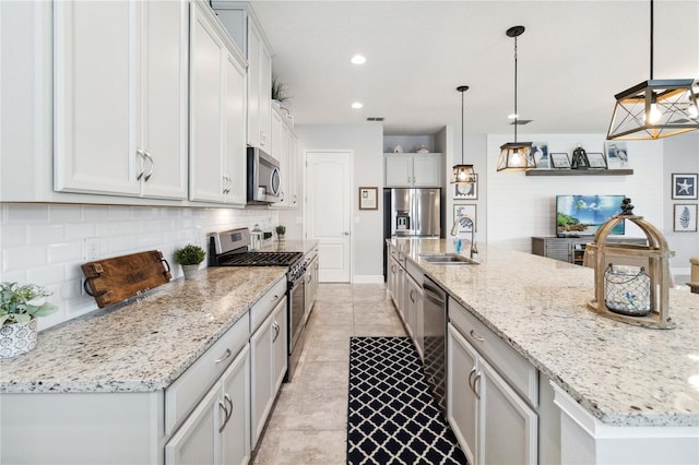 5025 Sunfalls Ave, Saint Cloud, FL 34772 - kitchen featuring stainless steel appliances, a sink, a large island with sink, decorative backsplash, and light stone countertops