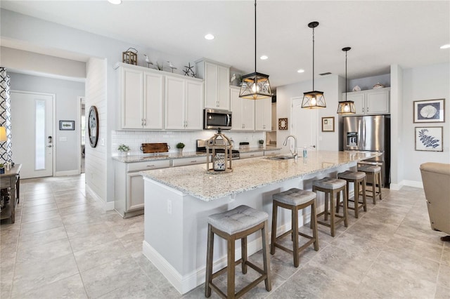5025 Sunfalls Ave, Saint Cloud, FL 34772 - kitchen with stainless steel appliances, a breakfast bar area, a sink, a large island with sink, and recessed lighting